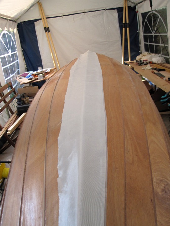La bande de tissu de verre est positionnée pour couvrir les deux bordés de fond, le tissu est bien lissé sur le bois. 