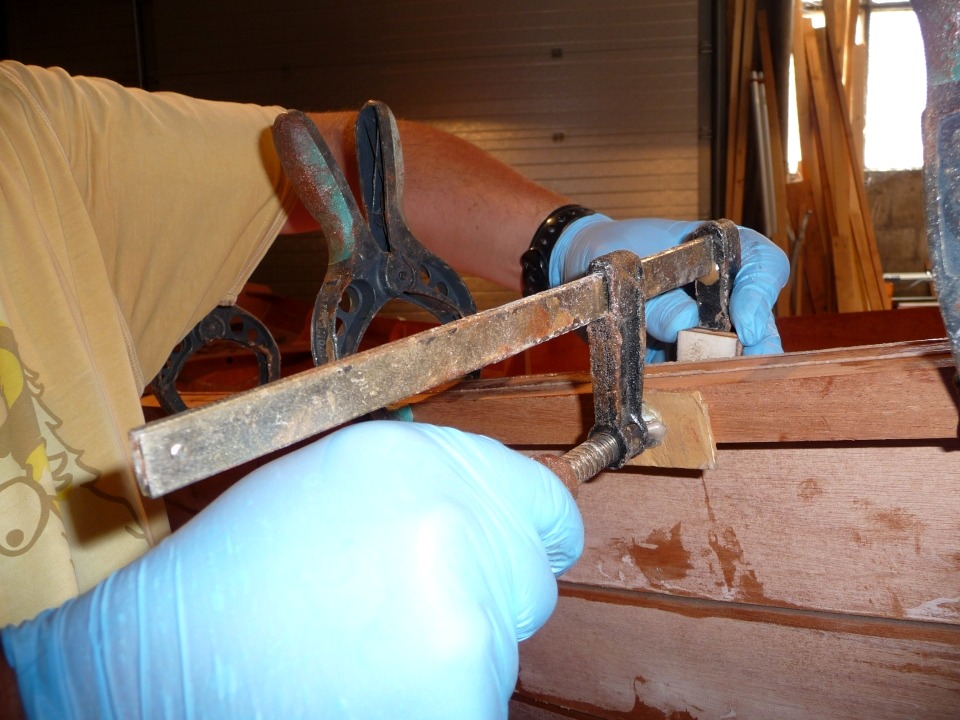 Nous posons des presses en complément, puis en remplacement des pinces. De petites cales en contreplaqué jouent le rôle de martyrs pour protéger le bois des empreintes des presses. 