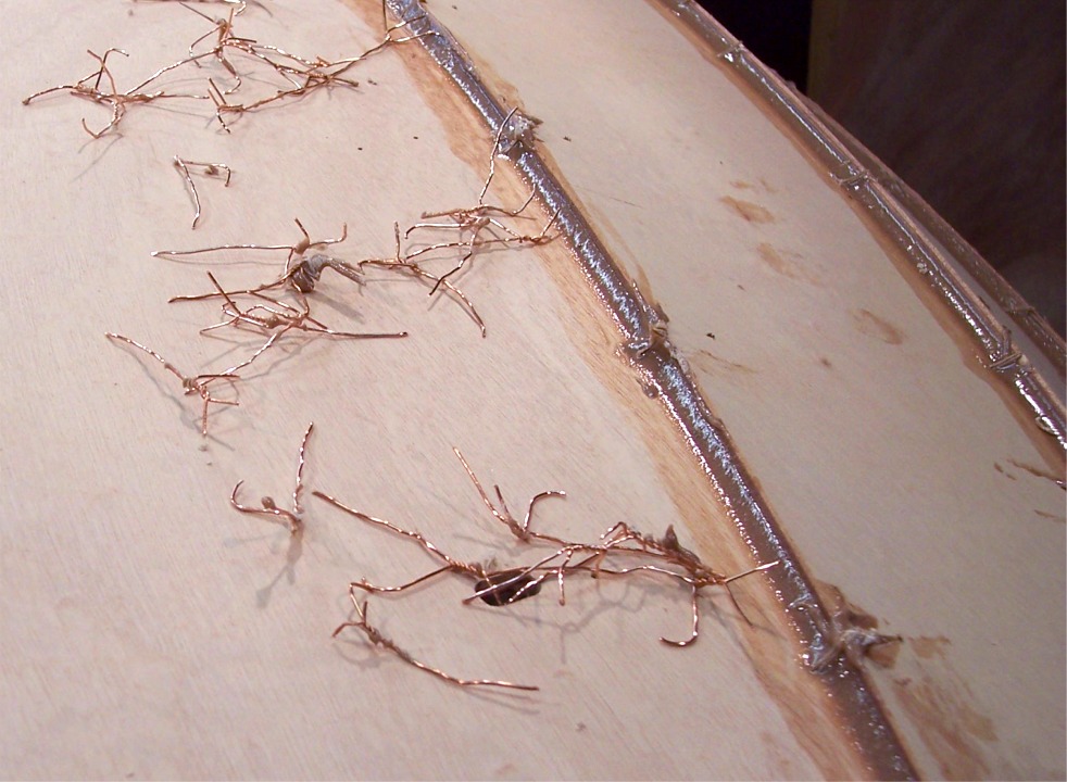Ce gros plan montre l'état des joints après extraction des sutures. A l'endroit qu'occupait chaque suture, il y a un "ergot" ou une pointe dans la surface du joint d'époxy, que j'avais lissé à la cuiller afin de pousser l'époxy chargée au fond de la cavité entre les panneaux. Il faudra éliminer ces ergots et poncer la surface des joints avant de passer une seconde couche d'époxy chargée pour obtenir le joint final. 