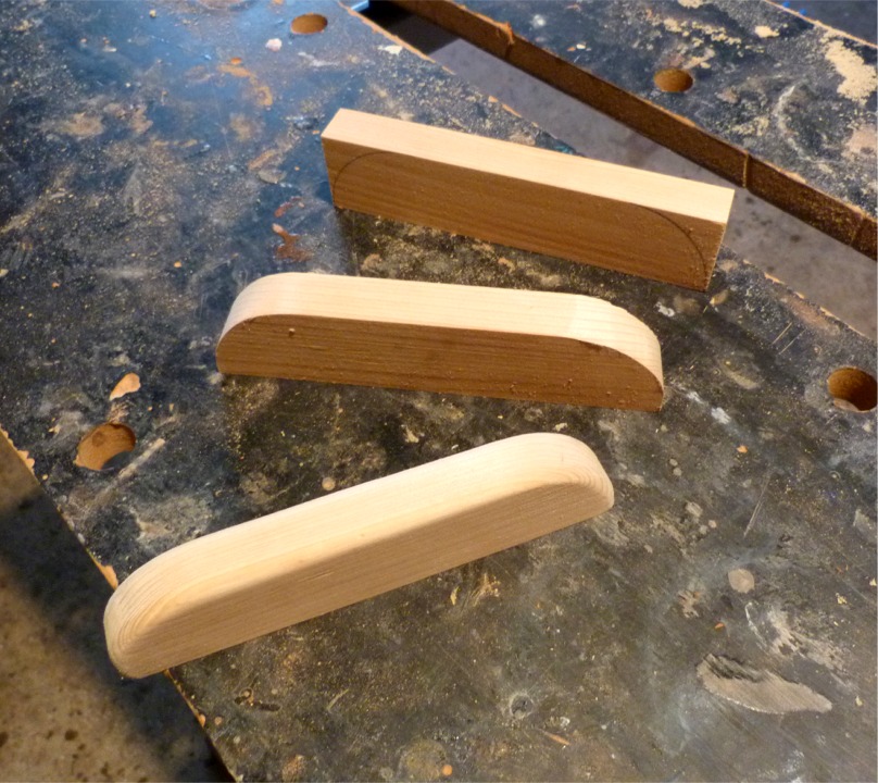 Le lendemain, je mets en forme les pièces de bois blanc qui vont servir de cale-pieds pour la rame. Il est impératif de pouvoir pousser sur les jambes, même en aviron "fixe" traditionnel, afin de pouvoir "tirer sur le bois mort". Il y donc trois paires de cale-pieds sur les bordés 1 du Skerry. Cette image montre la séquence des opérations : traçage au compas, découpe des angles en arc de cercle, puis passage à la défonceuse pour arrondir toutes les arêtes exposées (et un petit ponçage pour finir). 
