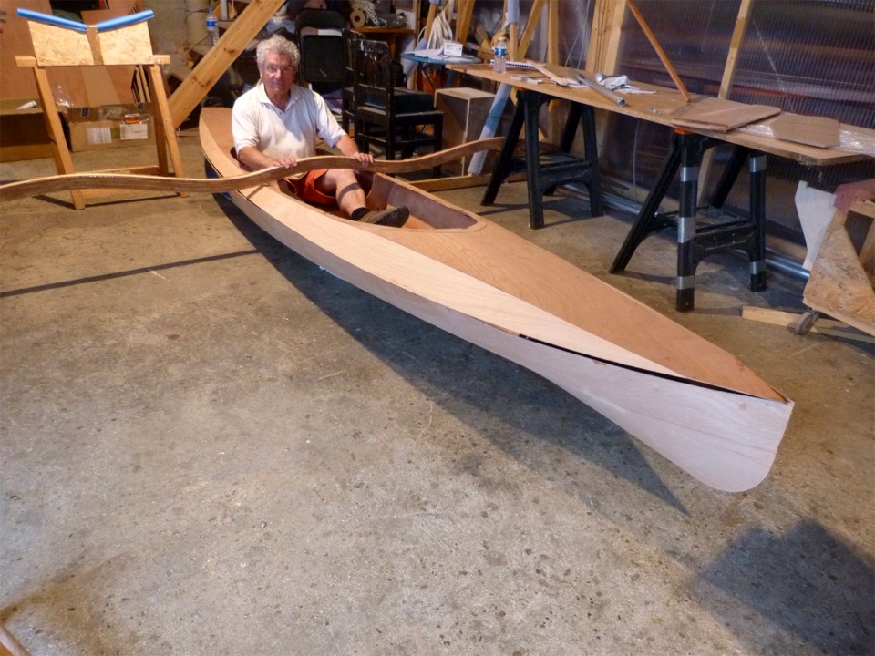 Retour au 4 juin : Pierre fait un essayage du siège arrière du Wood Duck Double. C'est le bras arrière qui traverse le cockpit du Wood Duck Double devant lui, le bras avant traversera sur le pont devant le cockpit. Nous avons posé le kayak sur des coussins afin d'éviter d'abîmer le fond du bateau, car l'extérieur de la coque n'est pas encore stratifié. On voit que le pont n'est que posé sur la coque, pas encore collé. 