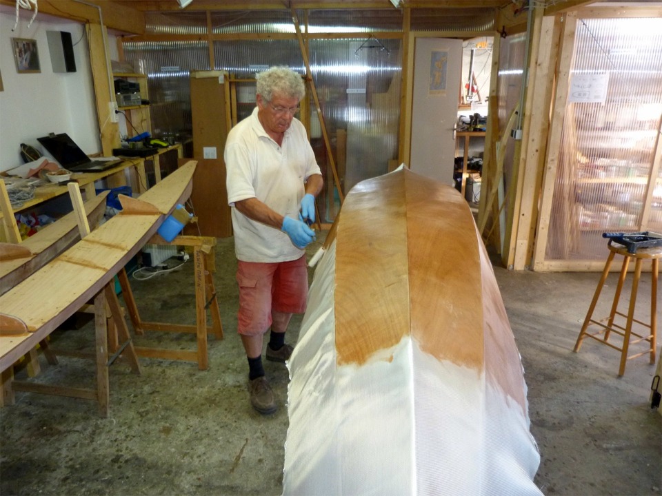 Pierre fait la stratification de l'extérieur de la coque du Wood Duck Double au rouleau : cette technique est plus facile que la raclette sur les parois quasi-verticales des panneaux latéraux, on prend nettement moins de résine dans les chaussures... 