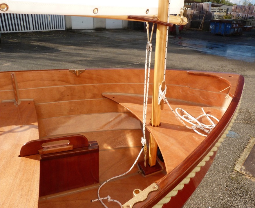 La voile est tenue verticalement par sa drisse (que l'on voit ici au taquet) et par ce palan à deux brins frappé sur la bôme juste en arrère du point de pivotement sur le mât. De ce fait, ce palan a une double fonction : d'abord il exerce une tension sur le guindant, et ensuite il joue également le rôle le hale-bas de bôme, grâce au court bras de levier entre son capelage et le point d'amure. Il est impératif que ce palan soit bien étarqué pour que la voile soit bien établie. Il est toujours navrant de voir des voiles au tiers avec un pli entre le point d'écoute et le haut du guindant sur l'avant de la vergue à cause d'une tension insuffisante sur l'amure.