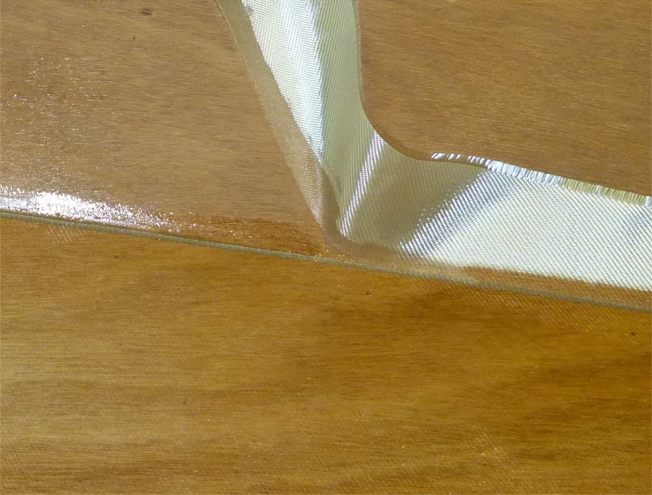 Je coupe le tissu non saturé à l'aide de la pointe d'un cutter en m'appuyant sur le bord extérieur des joints ou joints-congés. J'enchaîne 3 heures plus tard (en fait dès que l'époxy de stratification ne colle plus au doigt) avec une couche de remplissage de la trame. 