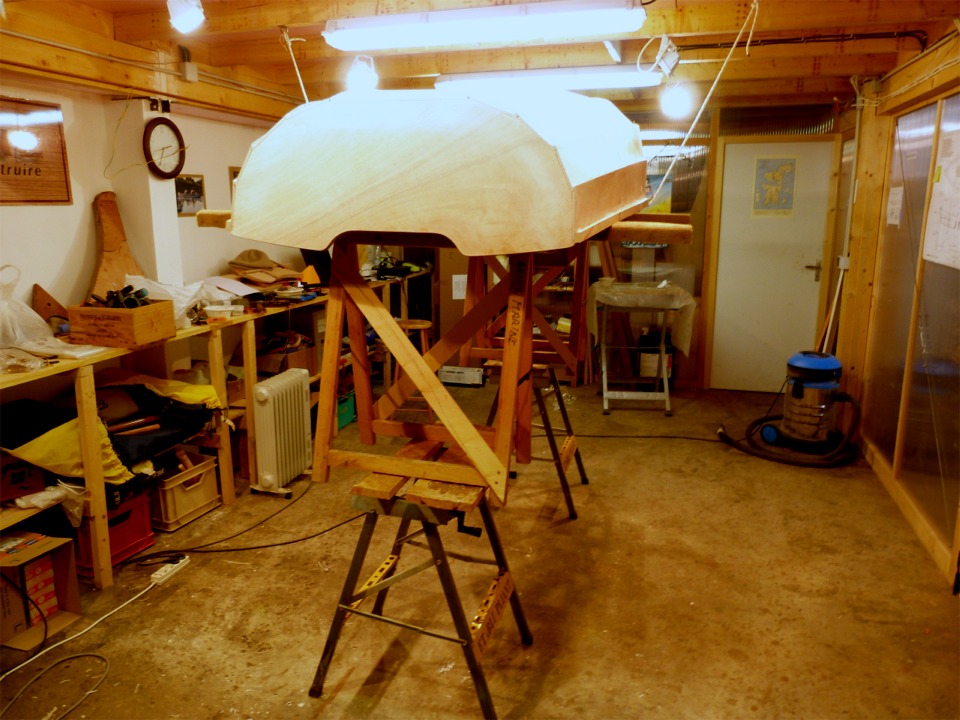 J'ai juché la Prame d'Eastport en hauteur afin de faire les joints-congés entre le bord supérieur des cloisons et le bord inférieur des sièges. Je me répète, mais je trouve que le confort de travail que l'on a à avoir les joints à hauteur des yeux vaut largement le petit effort de grimper le bateau en altitude. Notez la sauvegarde (bout blanc) qui sécurise l'installation. 