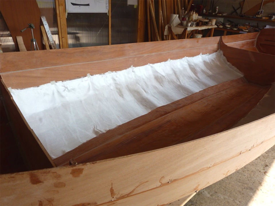 J'ai scotché le haut du tissu afin qu'il tienne en place en attendant de le saturer de résine époxy. J'ai prévu de remplacer ces deux grammages et ces trois pièces de tissu de verre par deux pièces de 200 grammes qui seront simplement croisées sur la sole. L'extérieur de la coque sera stratifié sur la même zone que celle qui est couverte par le premier tissu à l'intérieur : sole et 4 bordés de fond. 
