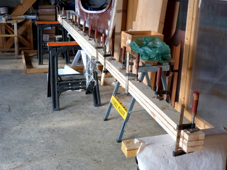 Je colle ensemble les trois lattes de pin de 4.95 m de long qui vont constituer le mât. J'ai considéré évider partiellement la couche centrale afin d' alléger un peu le mât mais je préfère privilégier sa solidité. 
