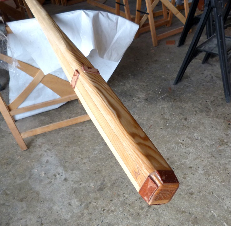 Je termine en passant une couche d'époxy sur le mât poncé, et en collant des cales d'étambrai et de pied en contreplaqué makoré (très dur) et profilées en biseau. L'intérêt de ces cales est d'amener le mât à la section précise des ouvertures de l'étambrai et du pied afin qu'il tienne bien en place. La dureté du makoré assure qu'il ne "collrae" pas lorsqu'il sera temps de démâter. 
