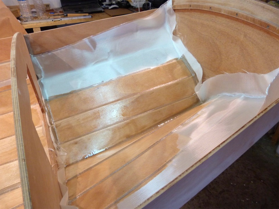 A chaque fois, je suis étonné par ce tissu qui devient transparent lorsqu'il est saturé de résine... Le tissu est assez large pour couvrir les 8 bordés de fond de la yole sur toute sa longueur. Dans le compartiment arrière, nous pourrions couvrir 5 bordés de chaque bord, mais à quoi bon (à part ajouter du poids). Nous allons donc saturer le tissu sur le bordé 4 tribord, et terminer symétriquement sur bâbord.