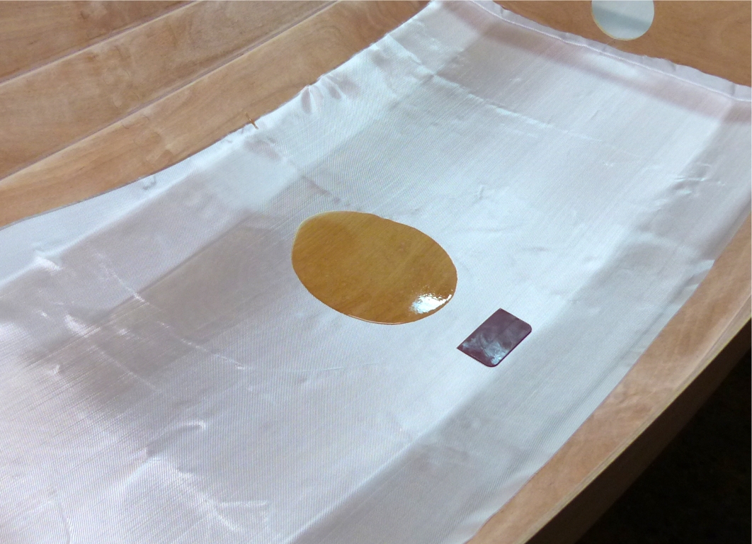 Je drape trois pièces de tissu de verre sur la surface intérieure basse de la coque. En effet, la stratification est volontairement limitée à la sole et aux bordés 1, car cela suffit à rigidifier la coque et à protéger la surface intérieure dans la zone où elle sera piétinée. Le surpoids d'une stratification intégrale serait peu justifié. De plus, les tissus les plus courants sont disponibles en largeur d'un mètre, ce qui convient à la zone visée. Il n'y a qu'à l'avant que je couvre aussi les bordés 2 afin de rigidifier un peu plus la proue. 