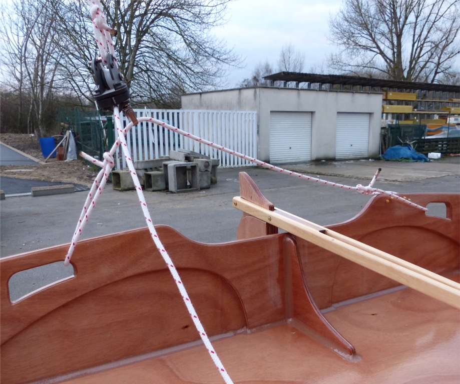 Du côté de l'écoute, la poulie basse du palan circule librement sur une patte d'oie nouée entre les deux poignées du tableau arrière : on règle sa longueur et l'emplacement des noeuds pour déterminer le débattement latéral de la poulie sur cette barre d'écoute textile. 
