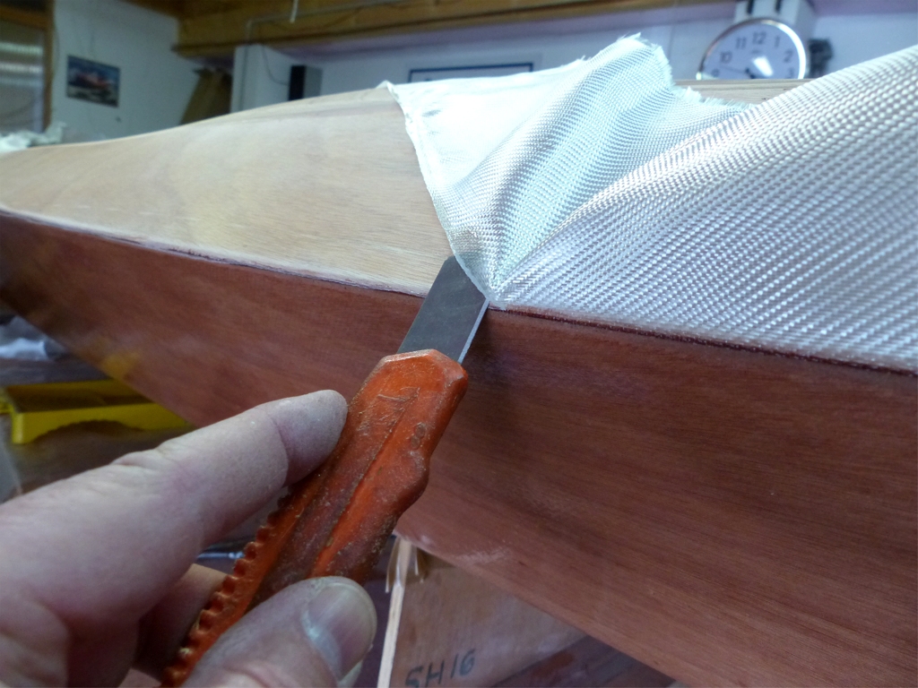 En parlant de couper des fibres, nous avons remis le Wood Duck à l'endroit après que l'époxy ait commencé à durcir, et nous coupons l'éxcédent de tissu non saturé. Au bout de 4 heures, l'époxy est suffisamment dure pour "tenir" les fibres, mais encore facile à couper au cutter. 