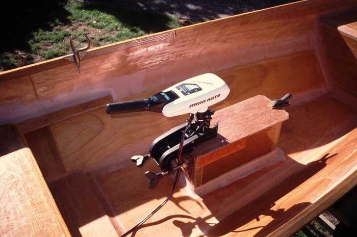 Pendant que nous parlons de moteur (si, si, c'est de ça que nous parlions avant de parler de ponçage), voici une autre solution sur un bateau très similaire au Skerry : un puits assez grand pour pouvoir installer ou démonter le moteur à flot, fixé sur la sole par des joints-congés. Le capot qui obture l'ouverture autour de l'arbre est juste tenu à l'aide d'une pince (on pourrait trouver une solution plus élégante). La position juste en arrière du banc central est intéressante, car l'opérateur peut être assis au centre de gravité du bateau. Par contre, il faudra être prudent dans les manoeuvres, car le moteur ne sera pas très directif. 