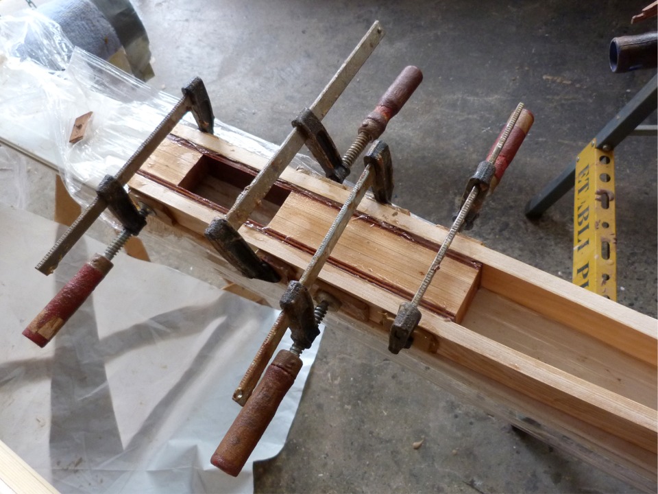J'ai d'abord construit une "caisse" qui chevauchera la tête du gouvernail. Deux lattes fines (13 mm d'épaisseur) de pin sont collées autour de cette caisse de 50 mm de large et sont sollées entre elles pour former la poignée. Les deux lattes de contreplaqué makoré renforcent et rigidifient la partie la plus sollicitée de la barre. 